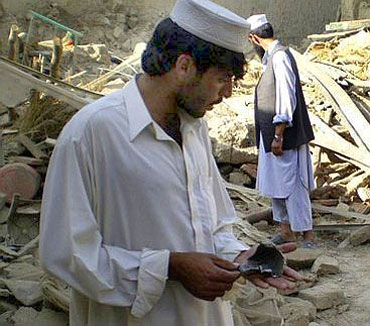 Pakistani villagers pick up rocket fragments after a drone strike