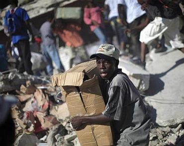 A youth loots products from a destroyed store in Port-au-Prince