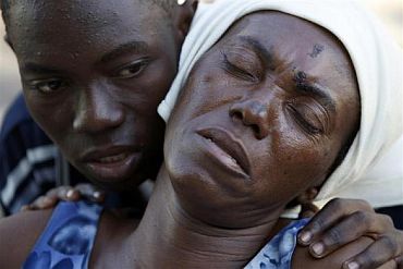 A girl comforts her injured mother at a makeshift hospital in Port-au-Prince
