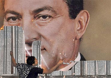 An anti-government protester defaces a picture of Egypt's President Hosni Mubarak in Alexandria
