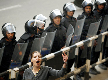 A member of an Egyptian activist group, shouts anti-government slogans in front of a police cordon during a demonstration in Cairo
