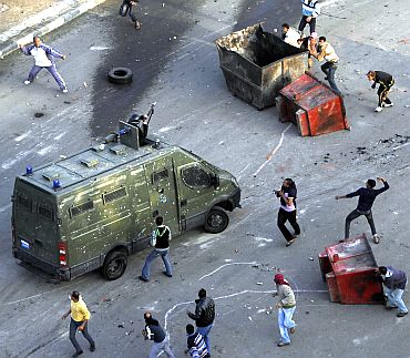 Egyptian anti-government protesters attack a riot police car at the port city in Suez