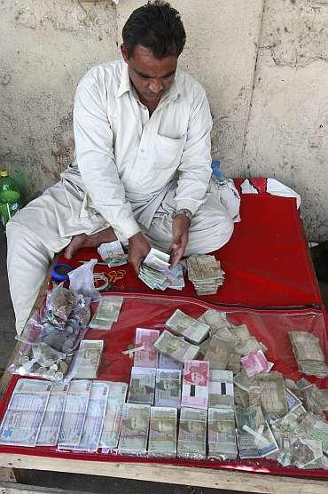 A currency dealer counts Pakistani rupees at his roadside shop in Karachi