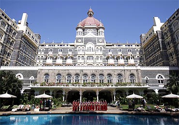 Staff of the Taj Mahal Palace hotel pose for a photo near the hotel's swimming pool