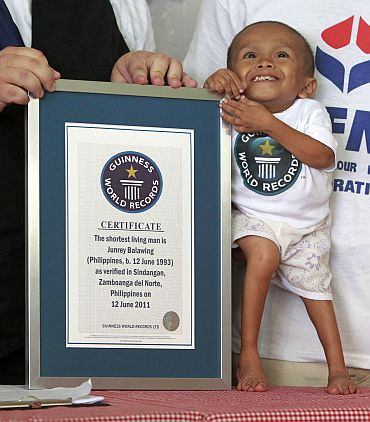 Junrey smiles as he stands beside his certificate as the World's Shortest Living Man