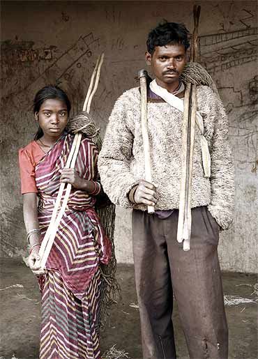 The Birhor Adivasi are the last remaining tribal group in Jharkhand who still attempt to live a hunting/ trapping/gathering life as they have for thousands of years. But due to the pressures of mining and logging, the habitat for wild animals is rapidly disappearing along with the Birhor's way of life which depended on plants and animals. Most have given up their formerly nomadic life to live in concrete government resettlement camps. Here, a Birhor couple have returned to their resettlement camp from an unsuccessful hunt with their traditional nets. On the wall behind them can be seen graffitied images of coal trucks, the new reality they are facing.