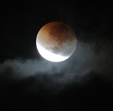 A lunar eclipse is visible through a gap in storm clouds over Sydney in the early hours of June 16