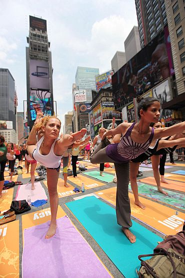 Naty Horev (L) and other enthusiasts perform yoga in Times Square