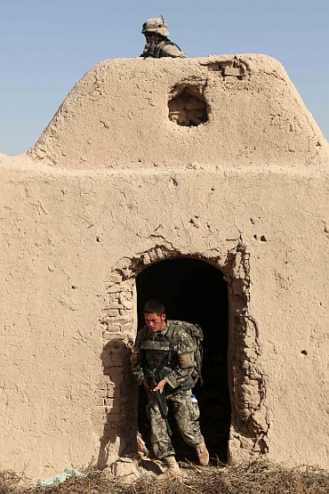 A US Marine, top, and an Afghan National Army soldier clear a building during a patrol in Sangin Valley, Helmand province, Afghanistan