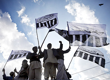 Supporters of Jamaat-ud-Dawa hold party flags during a rally against Davis in Lahore