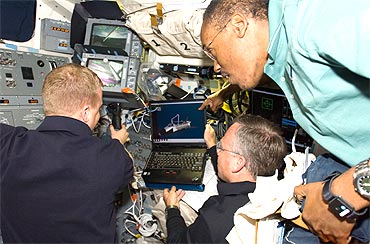 Discovery Pilot Eric Boe (L), Commander Steve Lindsey and mission specialist Alvin Drew (R) work on the aft flight deck of the shuttle