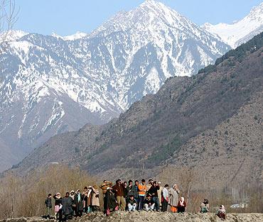 Local people look on as security personnel search Afghani's vehicle after the encounter
