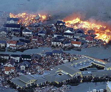 Houses swept out to sea burn following a tsunami and earthquake in Natori City in northeastern Japan