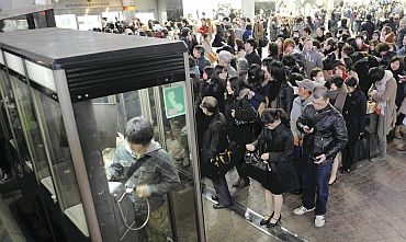 People line up in front of public telephone booths at Shibuya station in Tokyo