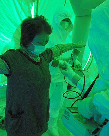 Medical staff use a Geiger counter to screen a woman for possible radiation exposure at a public welfare centre in Hitachi City