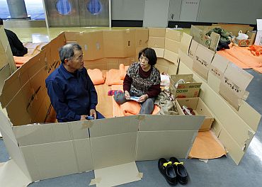 People who evacuated from Futaba, a city near the quake-stricken Fukushima Daiichi nuclear power plant, rest in a space cordoned off with cardboard in a hallway at the evacuees' new shelter in Saitama