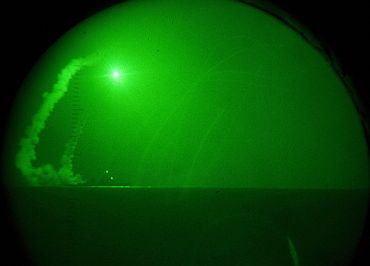 Seen through night-vision lenses aboard amphibious transport dock USS Ponce, the guided missile destroyer USS Barry fires Tomahawk cruise missiles in support of Operation Odyssey Dawn