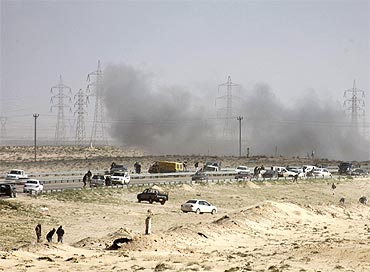 Smoke from a tank shell explosion rises over rebel vehicles just outside the northeastern Libyan town of Ajdabiyah