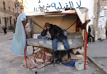 A protester sits in a makeshift shelter on a street during an anti-Gaddafi demonstration in Benghazi