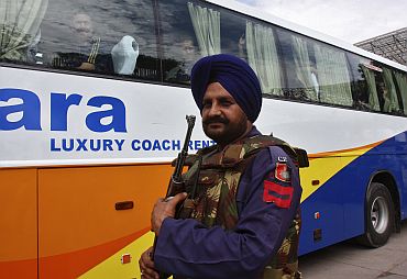 A security personnel stands guard in front of a bus carrying cricketers