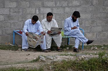 Men read newspapers while sitting near the compound where US Navy SEAL commandos reportedly killed bin Laden in Abbottabad