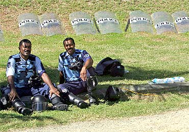 Policemen rest in front of a row of riot shields on the grounds of the country's Parliament House