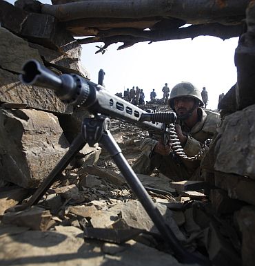 A Pakistani soldier holds a machine gun as he poses for the media during an operation organized by the army on top of a mountain near Sherwangi Tor village, located in South Waziristan