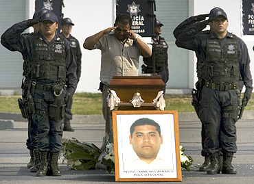 Mexican federal police officers salute during a ceremony in honour of officer Pedro Camacho, who was killed during an operation against Joaquin Guzman's drug cartel