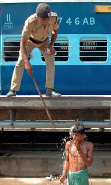 A policeman tries to stop a boy from taking bath from railway hose pipe in Patna