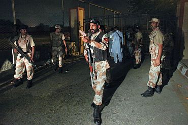 Military officials gesture to journalists to stay away at an entrance to the Mehran naval aviation base