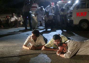Rescue workers and journalists take cover outside Mehran naval aviation base as a firefight continues between security forces and militants who attacked base in Karachi