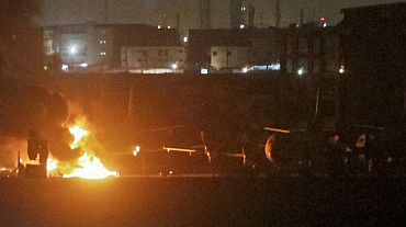 Men watch as a plume of smoke rises from the Mehran naval aviation base after it was attacked by militants in Karachi