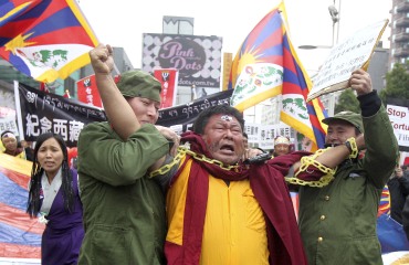 Activists dressed as Chinese soldiers and a Tibetan monk perform a street drama depicting Tibet's uprising 52 years ago against Chinese rule, in Taipei