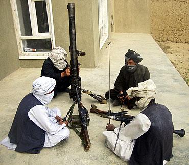 Taliban fighters pose with weapons as they sit in their compound at an undisclosed location in southern Afghanistan