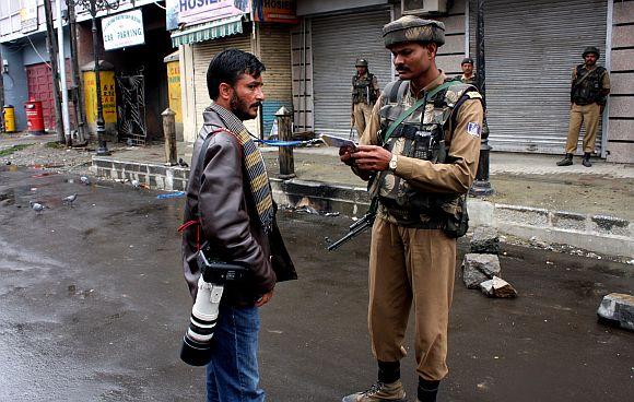 A soldier check the credentials of a photographer in Srinagar