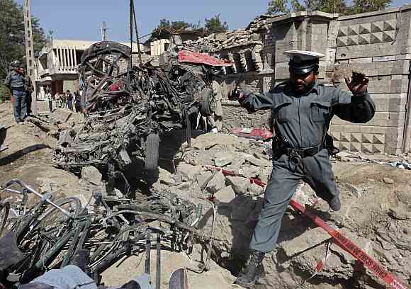 An Afghan policeman jumps over debris as he investigates at the site of a blast outside the Indian embassy in Kabul