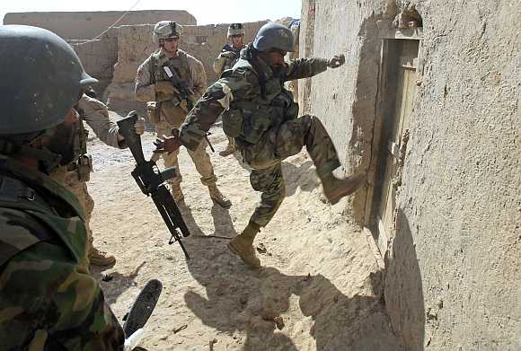 An Afghan soldier attempts to break open a door as US Marines from Bravo Company of the 1st Battalion, 6th Marines, look on during an operation to search for weapons in the town of Marjah, in Nad Ali district of Helmand province.