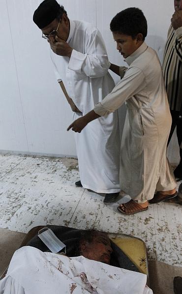 Libyan people visit the body of slain Libyan leader Muammar Gaddafi inside a storage freezer in Misrata