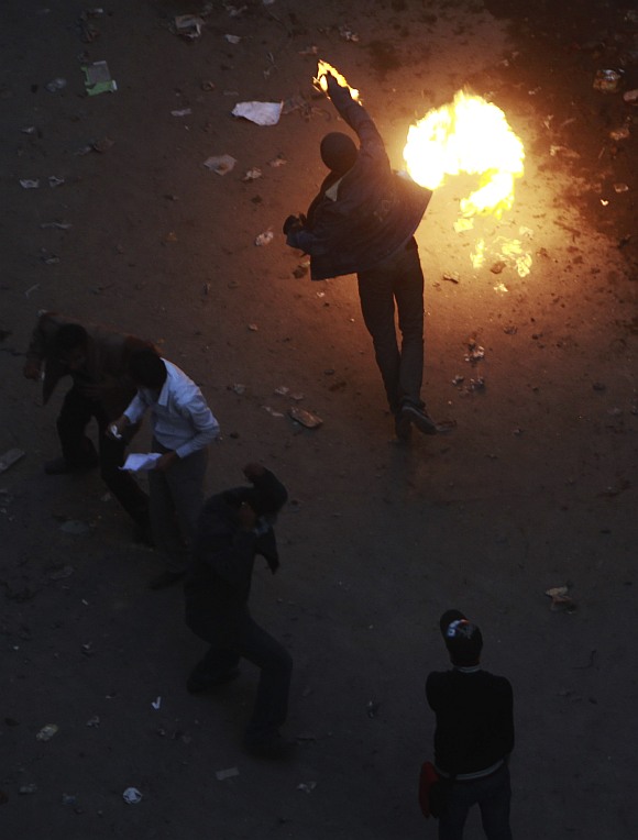 A protester throws a Molotov cocktail (petrol bomb) at riot police during clashes along a road which leads to the Interior Ministry, near Tahrir Square in Cairo