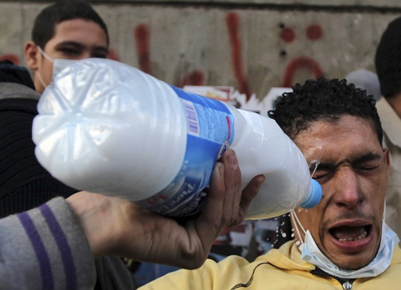 A protester has his eyes washed with milk to protect against tear gas during clashes with riot police along a road which leads to the Interior Ministry, near Tahrir Square in Cairo