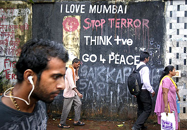 Pedestrians walk past graffiti that was painted after the 26/11 attacks outside a crematorium in Mumbai