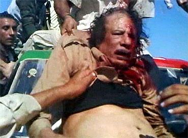 A fighter pulls Libya's former leader Muammar Gaddafi onto a miltary vehicle in Sirte in this still image taken from a video