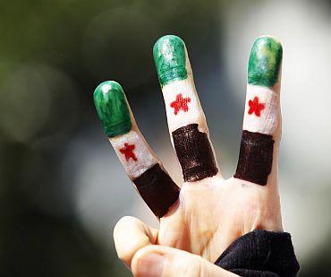 A Syrian opposition demonstrator, her fingers painted with the colours of Syrian flag