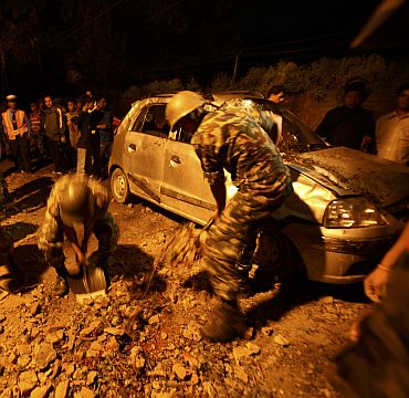 Members of the Nepalese army clear stones around a damaged car after the wall surrounding the British embassy collapsed during the 6.8 magnitude earthquake