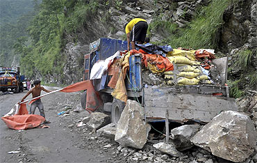 Workers try to salvage items from a supply truck loaded with cement bags after it was damaged by a landslide caused by Sunday's earthquake