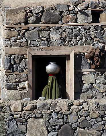 A woman carries a jar of water inside a house, as seen from a bunker of US soldiers in Ghaziabad district in Kunar province, eastern Afghanistan