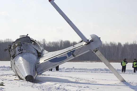 Emergency service workers stand near the tail section of the UTair airlines ATR 72 passenger plane that crashed near the Siberian city of Tyumen