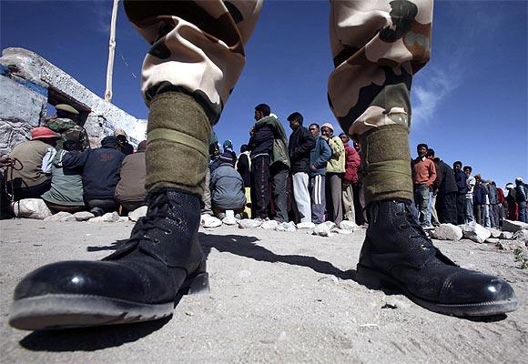 A policeman keeps guard as voters line up to cast their ballots outside a polling station