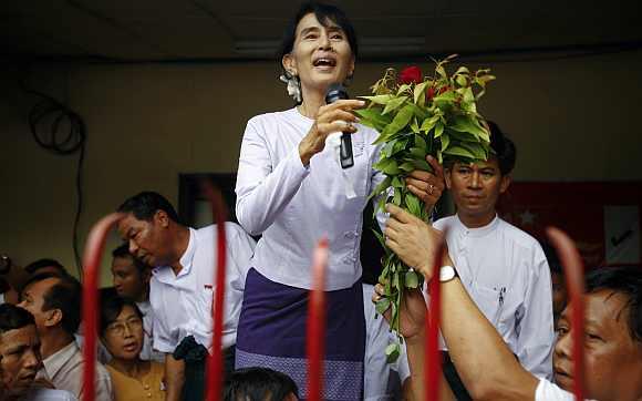 Myanmar's pro-democracy leader Aung San Suu Kyi receives flowers as she addresses supporters and reporters from the NLD office in Yangon