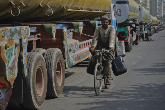 A man rides his bicycle past trucks which are carrying fuel for NATO forces in Afghanistan lined up along a road in Karachi